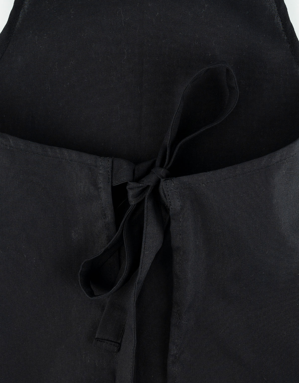 Siyah çocuk mutfak önlüğü giyen çocuk model; bir elinde turuncu merdane tutarken, sade ve baskısız önlük ön görünümde gösterilmektedir.