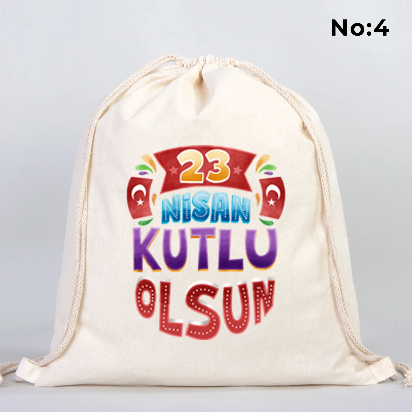 40x50 cm naturel renkli büzgülü bez çanta üzerinde “23 Nisan Kutlu Olsun” yazılı renkli çocuk figürleri baskısı, balon detayları ve kutlama temalı sınıf arka planı