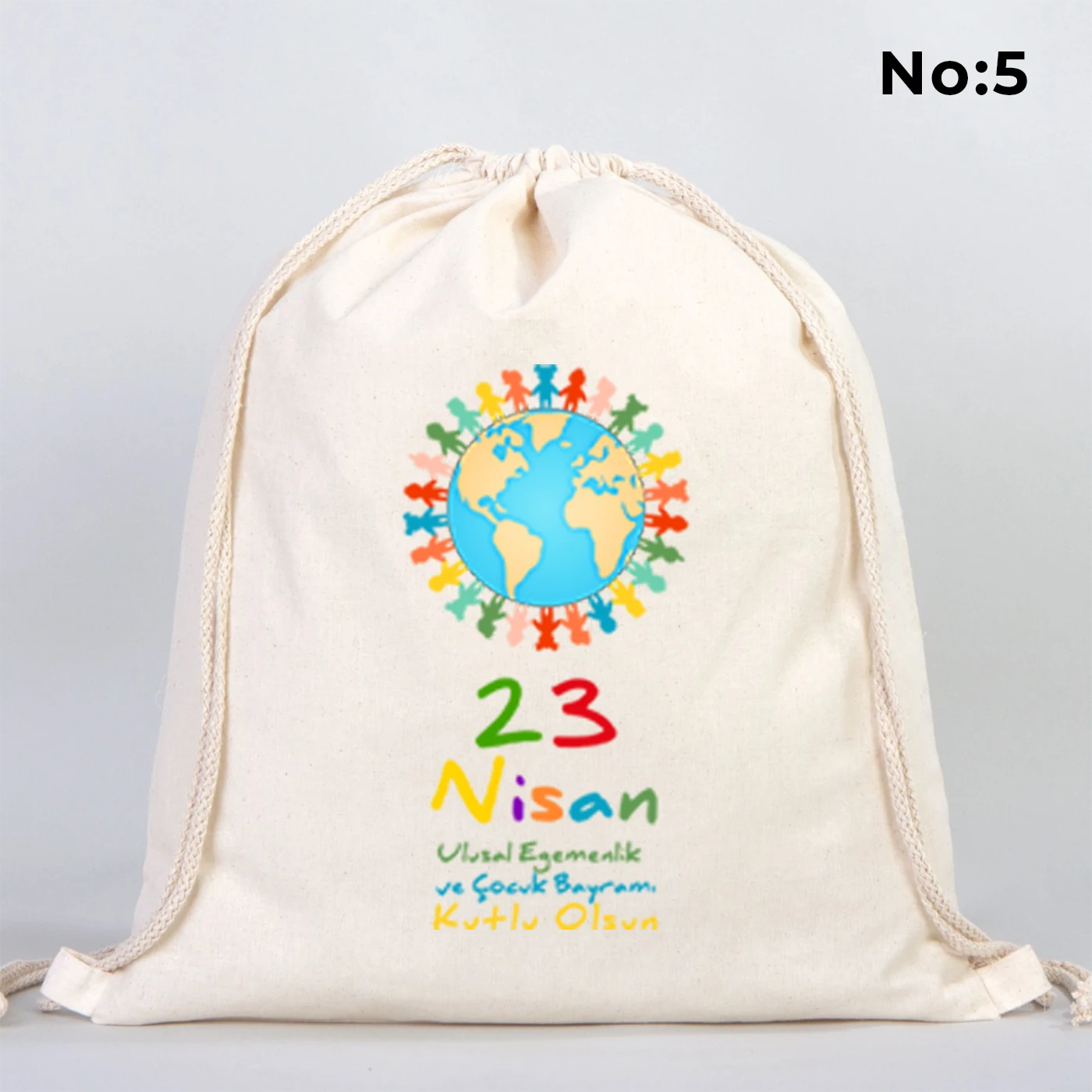 40x50 cm naturel renkli büzgülü bez çanta üzerinde “23 Nisan Kutlu Olsun” yazılı renkli çocuk figürleri baskısı, balon detayları ve kutlama temalı sınıf arka planı