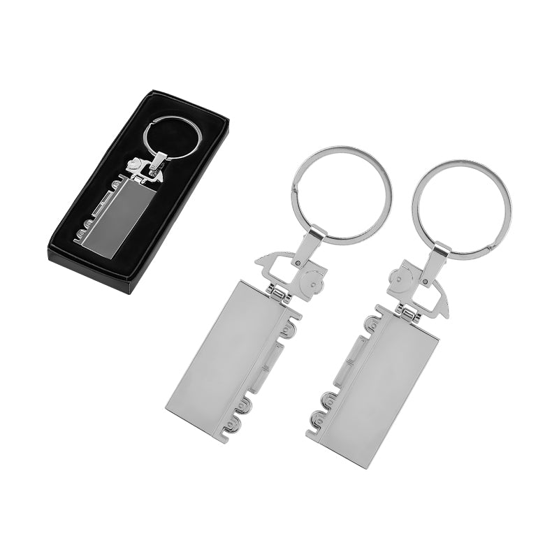 Gümüş renkli, tren vagonu şeklinde tasarlanmış metal anahtarlık; yan yana iki adet anahtarlık ve üstte hediye kutusu içinde sunulmuş hali görülüyor.