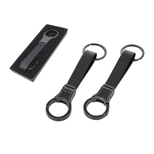 “Mat siyah metal gövdeye ve siyah deri kayışa sahip modern tasarımlı anahtarlık; iki adet anahtarlık ve üstte hediye kutusu içindeki sunumu görülüyor.”