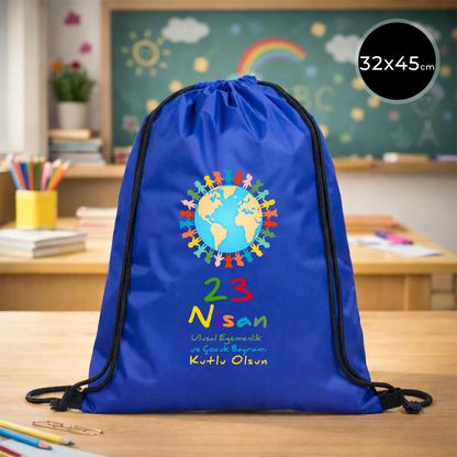 32x45 cm mavi büzgülü sırt çantası üzerinde dünya figürü, renkli çocuk silüetleri ve “23 Nisan Ulusal Egemenlik ve Çocuk Bayramı Kutlu Olsun” yazılı baskı, sınıf temalı arka plan