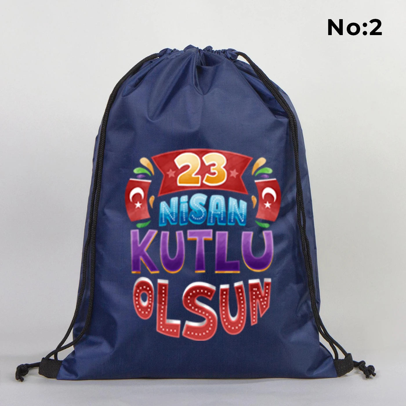 32x45 cm lacivert büzgülü sırt çantası üzerinde “Yaşasın 23 Nisan” yazılı çocuk temalı renkli baskı, roket ve kâğıt uçak detayları, kutlama temalı sınıf arka planı