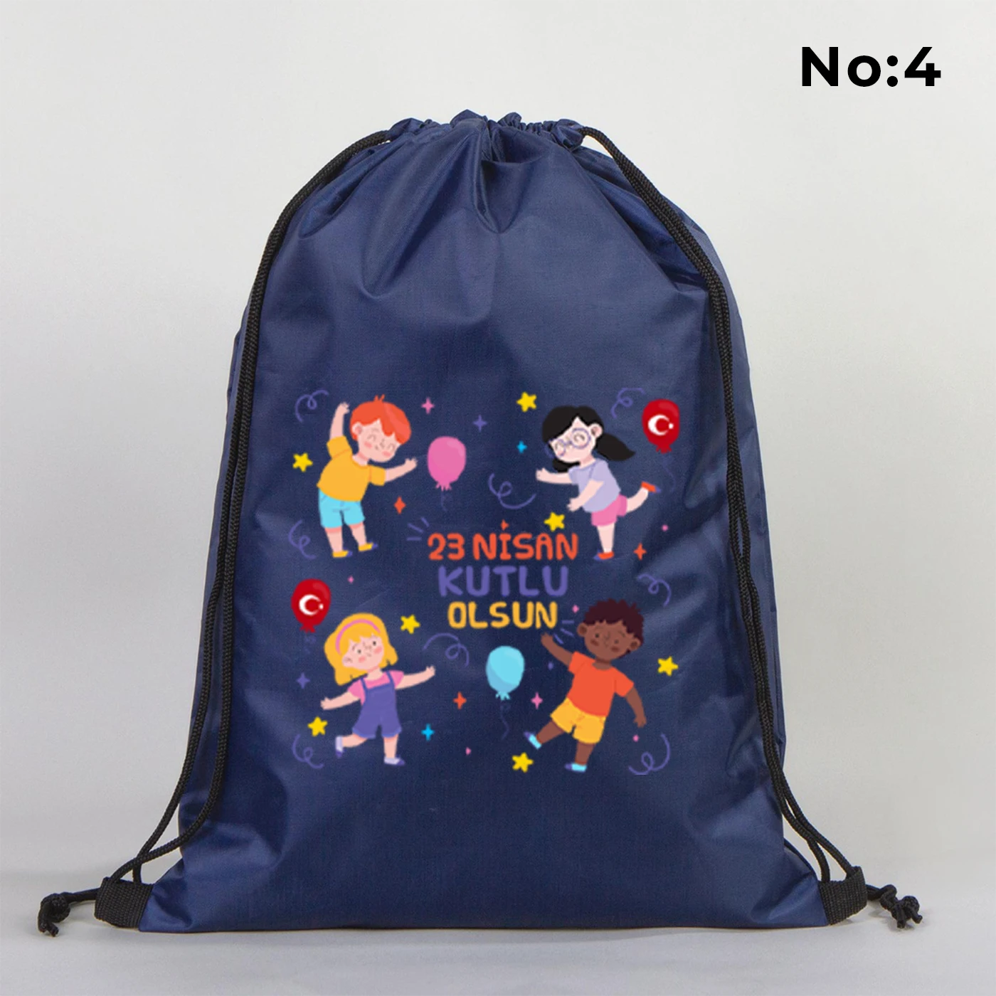 32x45 cm lacivert büzgülü sırt çantası üzerinde “Yaşasın 23 Nisan” yazılı çocuk temalı renkli baskı, roket ve kâğıt uçak detayları, kutlama temalı sınıf arka planı