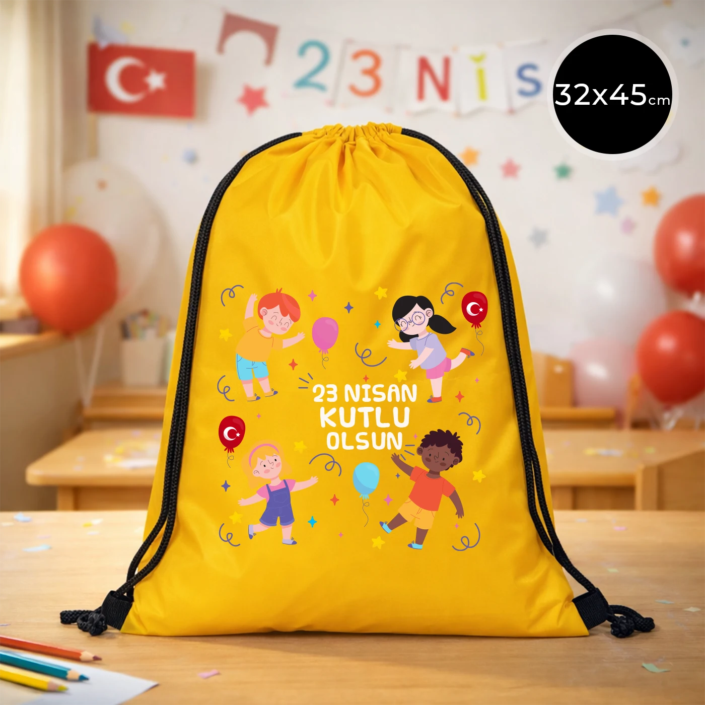 32x45 cm sarı büzgülü sırt çantası üzerinde “23 Nisan Kutlu Olsun” yazılı renkli çocuk figürleri baskısı, balon detayları ve kutlama temalı sınıf arka planı