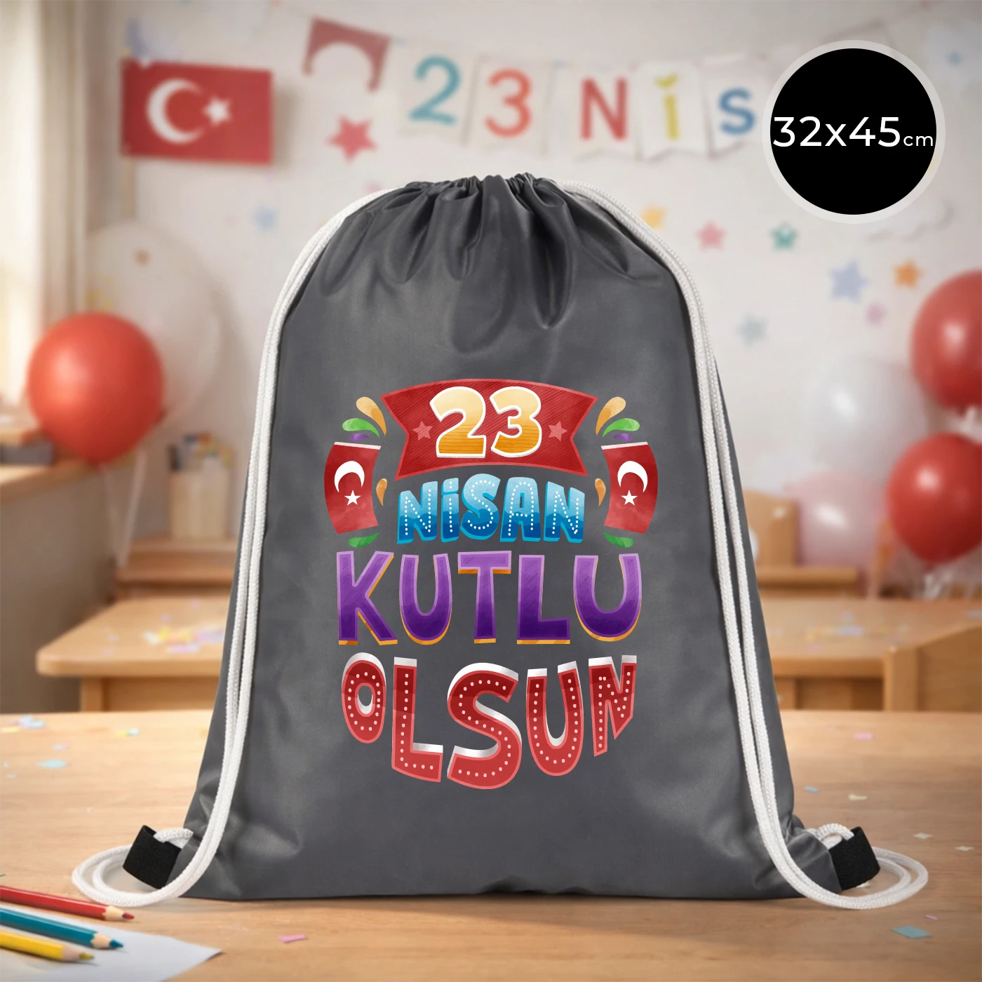 32x45 cm gri büzgülü sırt çantası üzerinde renkli “23 Nisan Kutlu Olsun” yazı baskısı, bayrak detayları ve kutlama temalı sınıf arka planı