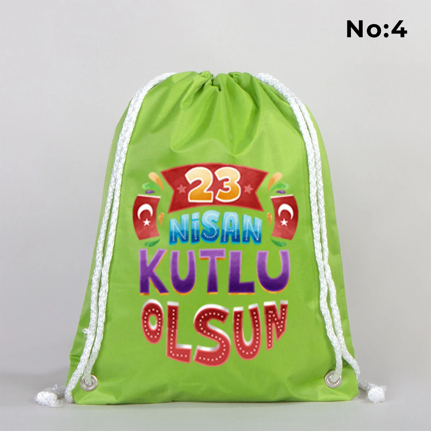 32x45 cm yeşil büzgülü sırt çantası üzerinde dünya figürü, renkli çocuk silüetleri ve “23 Nisan Ulusal Egemenlik ve Çocuk Bayramı Kutlu Olsun” yazılı baskı, kutlama temalı sınıf arka planı