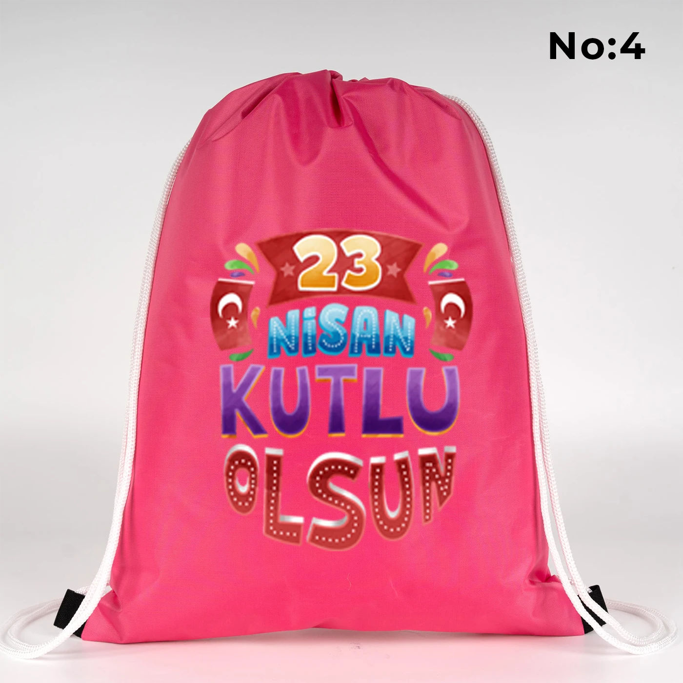 32x45 cm pembe büzgülü sırt çantası üzerinde “23 Nisan Kutlu Olsun” yazılı renkli çocuk figürleri baskısı, balon detayları ve kutlama temalı sınıf arka planı