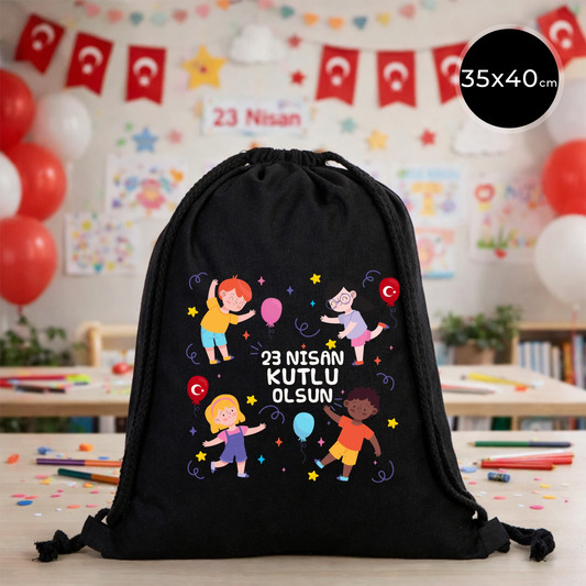 35x40 cm siyah büzgülü bez çanta üzerinde “23 Nisan Kutlu Olsun” yazılı renkli çocuk figürleri baskısı, balon detayları ve 23 Nisan temalı sınıf arka planı