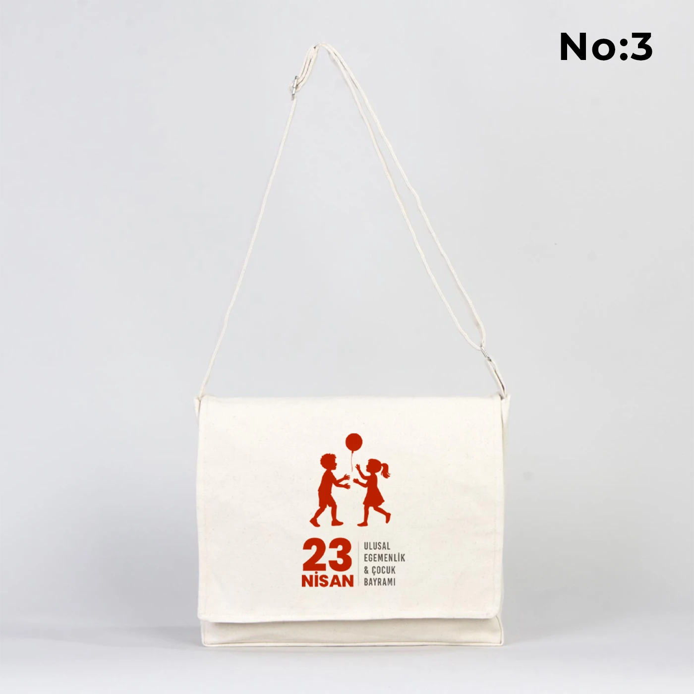 34x27x8 cm krem renkli kapaklı kumaş çanta üzerinde “23 Nisan Kutlu Olsun” yazılı renkli çocuk figürleri baskısı, geniş iç hacim ve uzun askı detayı