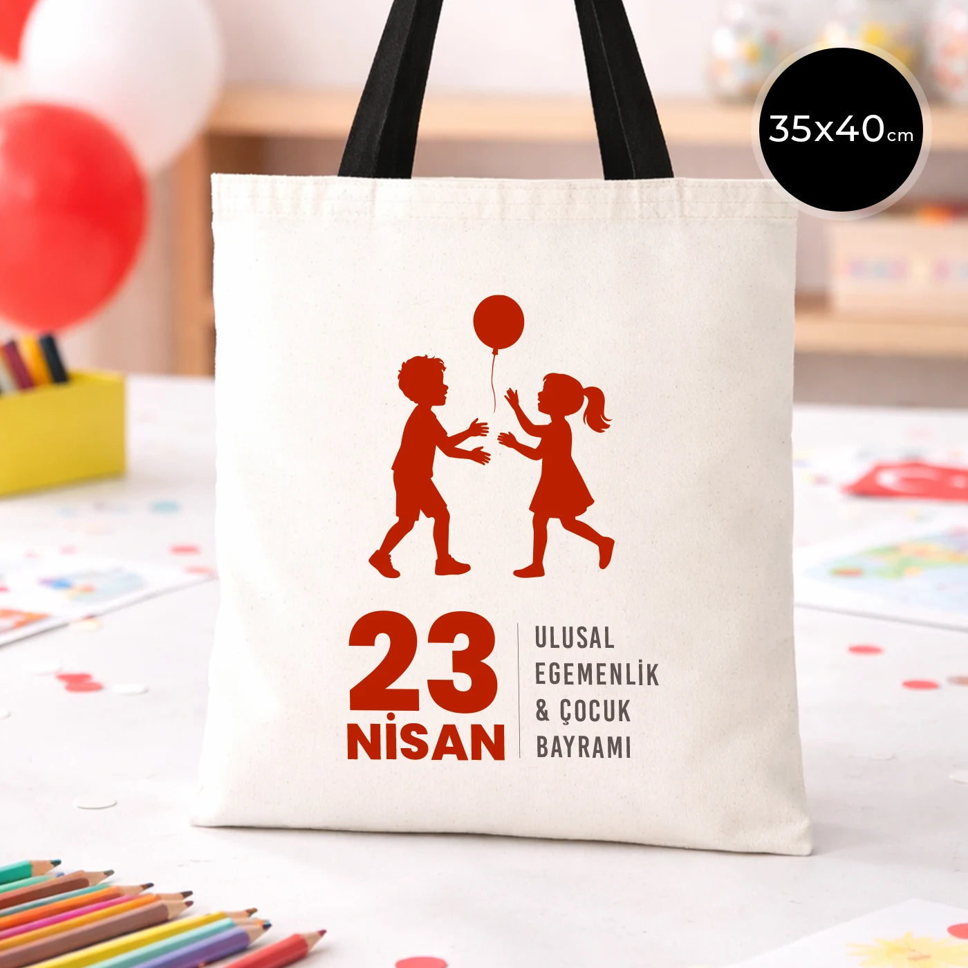 35x40 cm ham bez çanta üzerinde “23 Nisan Ulusal Egemenlik & Çocuk Bayramı” yazısı ve balonlu kız-erkek çocuk silüeti bulunan 23 Nisan temalı bez çanta.