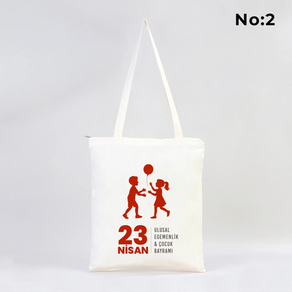 35x40 cm fermuarlı ham bez çanta üzerinde dünya etrafında renkli çocuk figürleri ve “23 Nisan Ulusal Egemenlik ve Çocuk Bayramı Kutlu Olsun” yazısı bulunan 23 Nisan temalı bez çanta.