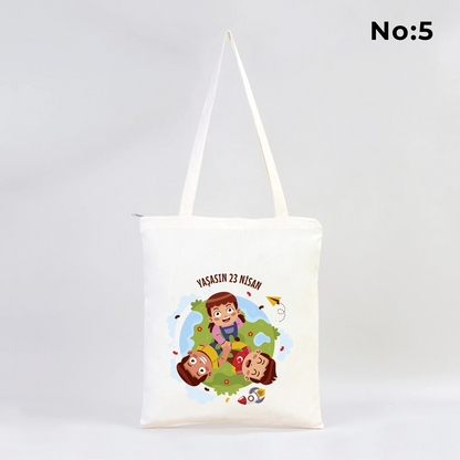 35x40 cm fermuarlı ham bez çanta üzerinde dünya etrafında renkli çocuk figürleri ve “23 Nisan Ulusal Egemenlik ve Çocuk Bayramı Kutlu Olsun” yazısı bulunan 23 Nisan temalı bez çanta.