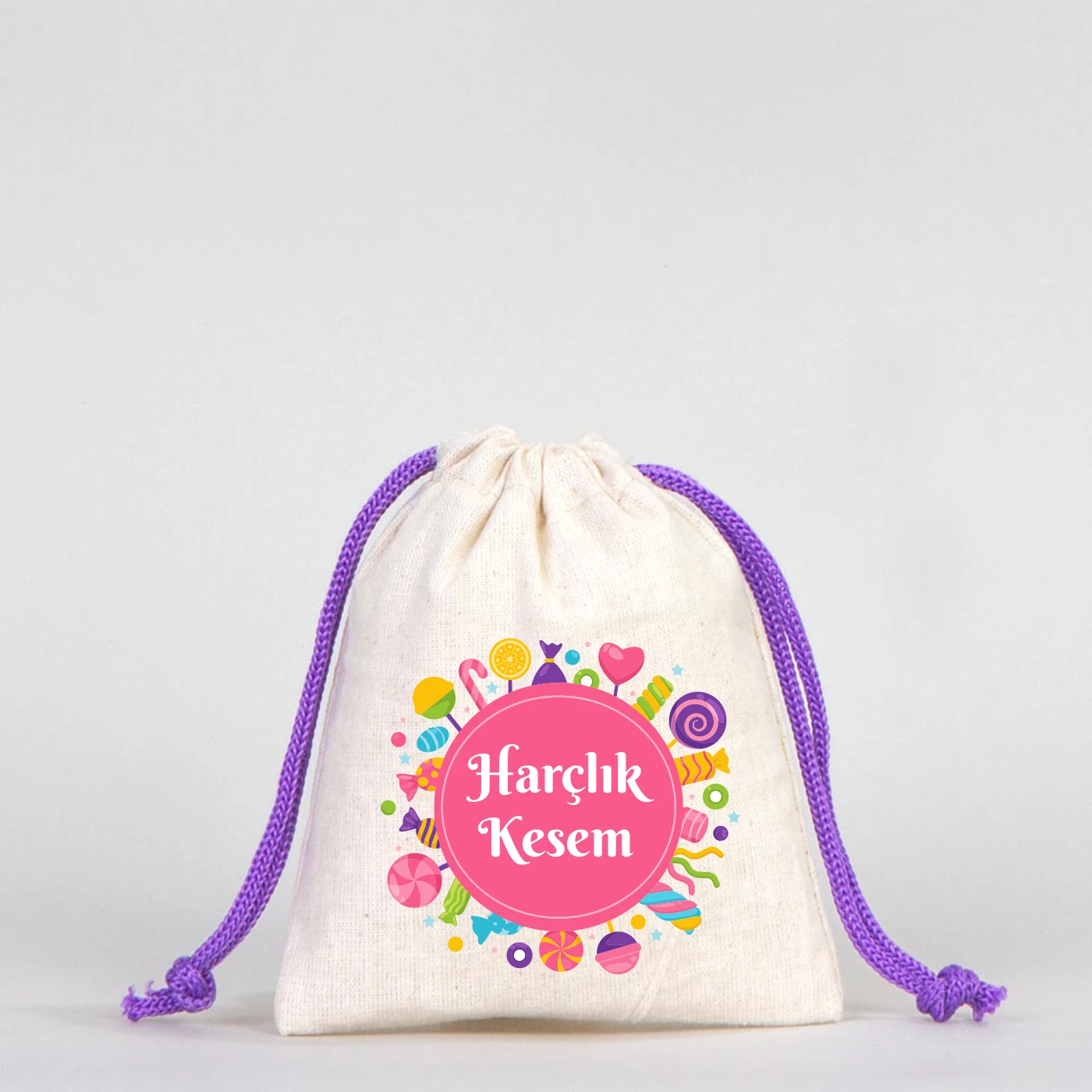 Beyaz fonda, mor büzgülü ipli, pamuk kumaş bayram harçlık kesesi, renkli şeker desenleri ve “Harçlık Kesem” yazısı