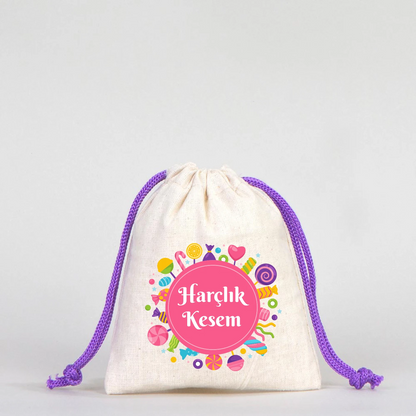 Beyaz fonda, mor büzgülü ipli, pamuk kumaş bayram harçlık kesesi, renkli şeker desenleri ve “Harçlık Kesem” yazısı