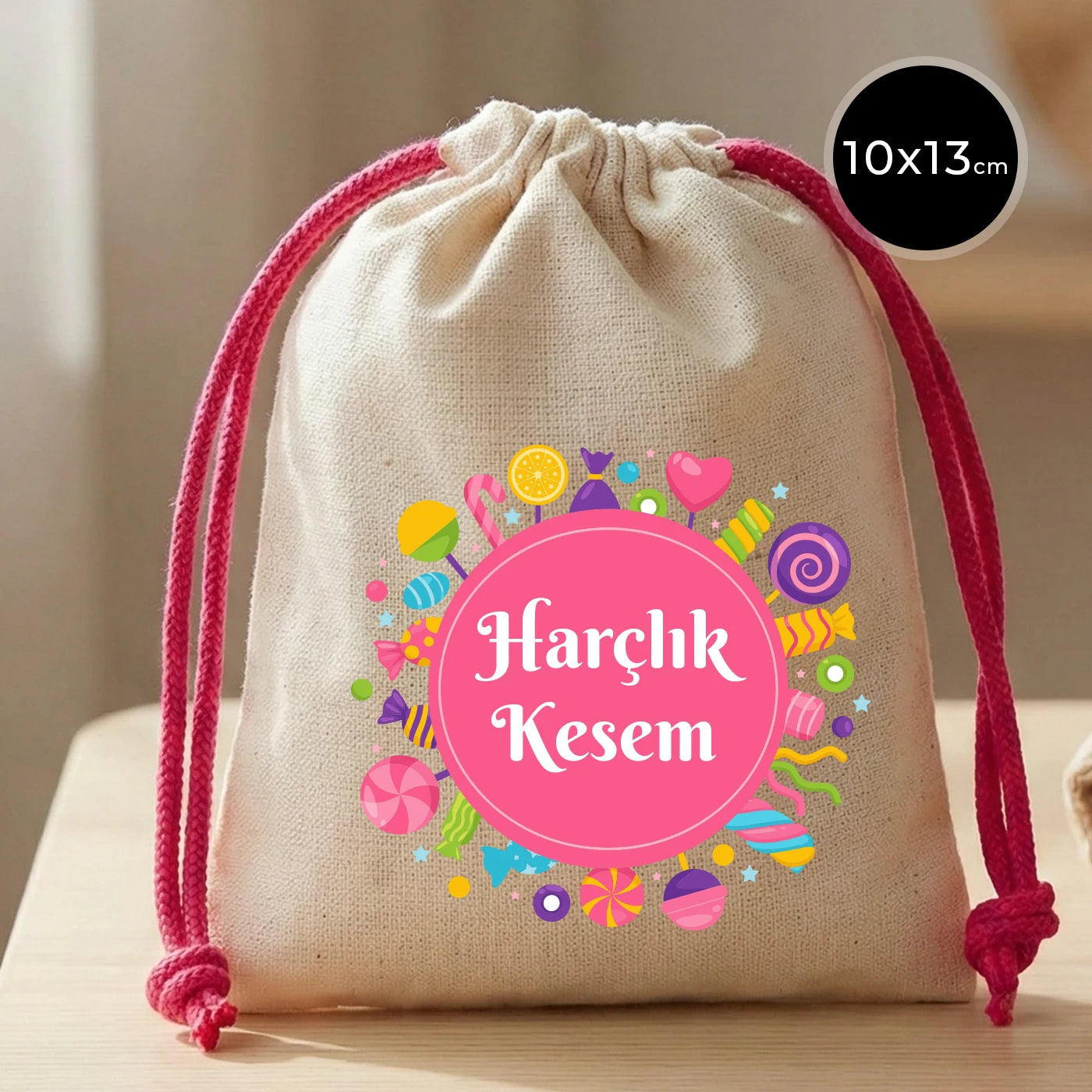 Fuşya ipli, 10x13 cm ölçülerinde, pamuk bezden yapılmış, üzerinde renkli şeker desenleri ve “Harçlık Kesem” yazısı bulunan bayram harçlık kesesi