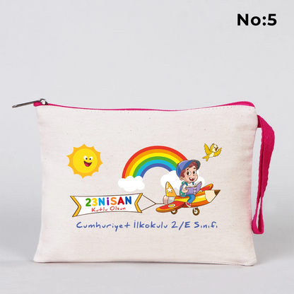 23 Nisan temalı 21x15 cm fermuarlı bez kalemlik üzerinde “23 Nisan Ulusal Egemenlik ve Çocuk Bayramı Kutlu Olsun” yazısı, ay ve yıldız üzerinde oturan iki çocuk illüstrasyonu ve okul - sınıf özelleştirilebilir alan.