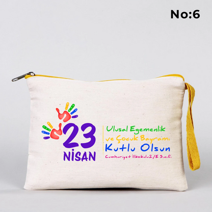 23 Nisan temalı 21x15 cm fermuarlı bez kalemlik üzerinde dünya etrafında el ele çocuk figürleri, “23 Nisan Ulusal Egemenlik ve Çocuk Bayramı Kutlu Olsun” yazısı ve okul - sınıf özelleştirilebilir alan.