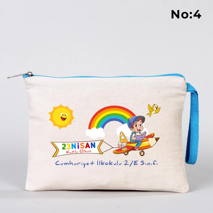23 Nisan temalı 21x15 cm fermuarlı bez kalemlik üzerinde “23 Nisan Ulusal Egemenlik ve Çocuk Bayramı Kutlu Olsun” yazısı, ay ve yıldız üzerinde oturan iki çocuk illüstrasyonu ve okul - sınıf özelleştirilebilir alan.