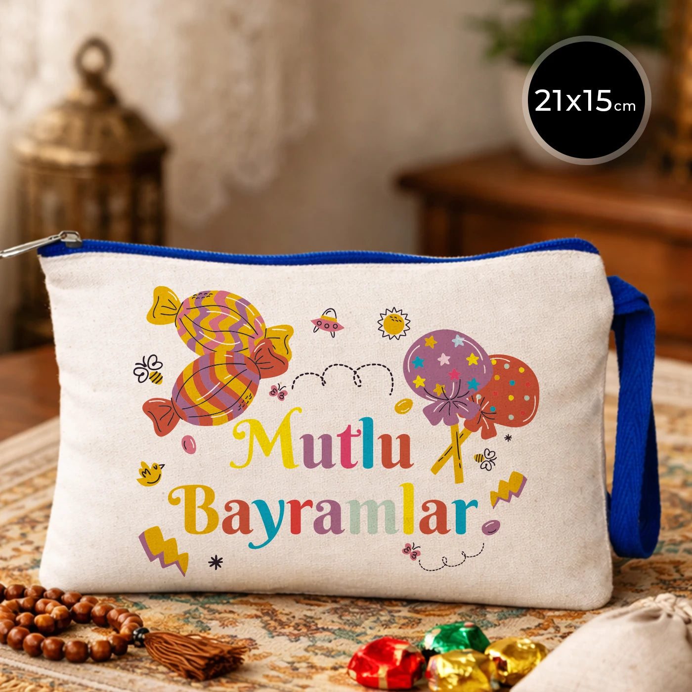 21x15 cm krem renk kanvas clutch çanta; lacivert fermuar ve lacivert bilek askısı detaylı. Ön yüzünde renkli “Mutlu Bayramlar” yazısı, şeker ve balon illüstrasyonları yer alıyor. Ürün, Bayram hediyesi ve harçlık/şeker sunumu için uygun, içi fermuarlı çok amaçlı küçük çanta.
