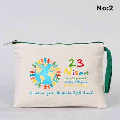 23 Nisan temalı 21x15 cm fermuarlı bez kalemlik üzerinde gökkuşağı, güneş ve uçaklı çocuk illüstrasyonu ile “23 Nisan Kutlu Olsun” yazısı ve okul - sınıf özelleştirilebilir alan.
