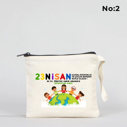 23 Nisan temalı 15x13 cm fermuarlı bez kalemlik üzerinde “23 Nisan Kutlu Olsun” yazısı, balonlu iki çocuk illüstrasyonu ve okul - sınıf özelleştirilebilir alan.