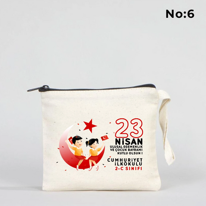 23 Nisan temalı 15x13 cm fermuarlı bez kalemlik üzerinde “23 Nisan Kutlu Olsun” yazısı, balonlu iki çocuk illüstrasyonu ve okul - sınıf özelleştirilebilir alan.