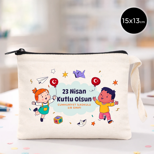 23 Nisan temalı 15x13 cm fermuarlı bez kalemlik üzerinde “23 Nisan Kutlu Olsun” yazısı, balonlu iki çocuk illüstrasyonu ve okul - sınıf özelleştirilebilir alan.