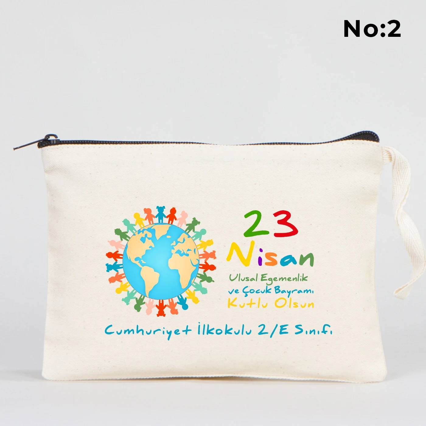 21x15 cm ölçülü, krem renkli fermuarlı kumaş kalemlik üzerinde “23 Nisan Kutlu Olsun” yazısı, balon tutan iki çocuk illüstrasyonu ve sınıf temalı arka plan