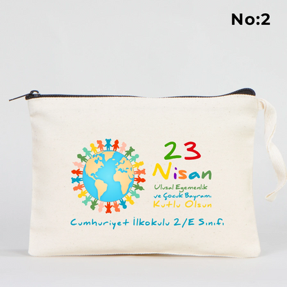 21x15 cm ölçülü, krem renkli fermuarlı kumaş kalemlik üzerinde “23 Nisan Kutlu Olsun” yazısı, balon tutan iki çocuk illüstrasyonu ve sınıf temalı arka plan