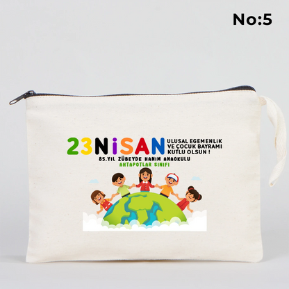 25x18 cm krem renkli fermuarlı kumaş kalemlik üzerinde 23 Nisan Ulusal Egemenlik ve Çocuk Bayramı baskısı, ay yıldız üzerinde oturan iki çocuk illüstrasyonu ve sınıf temalı arka plan