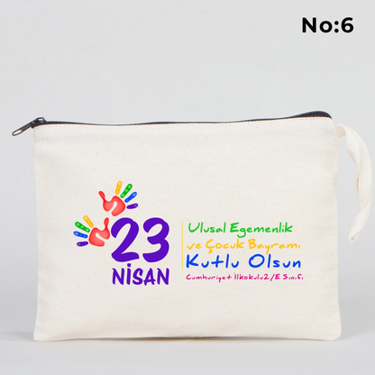 25x18 cm krem renkli fermuarlı kumaş kalemlik üzerinde 23 Nisan Ulusal Egemenlik ve Çocuk Bayramı baskısı, ay yıldız üzerinde oturan iki çocuk illüstrasyonu ve sınıf temalı arka plan