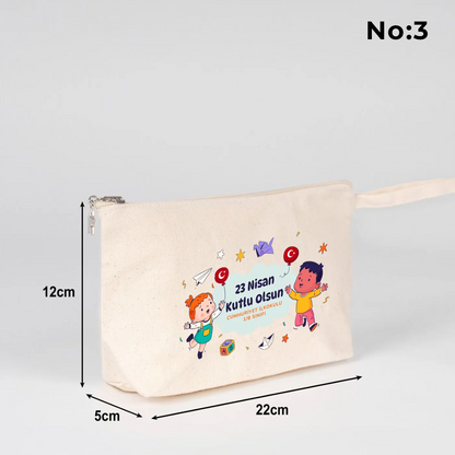 22x12x5 cm krem renkli fermuarlı kumaş kalemlik üzerinde yıldız fermuar ucu detayı, dünya figürü, renkli çocuk silüetleri ve “23 Nisan Ulusal Egemenlik ve Çocuk Bayramı Kutlu Olsun” yazılı baskı