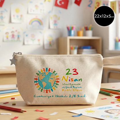22x12x5 cm krem renkli fermuarlı kumaş kalemlik üzerinde yıldız fermuar ucu detayı, dünya figürü, renkli çocuk silüetleri ve “23 Nisan Ulusal Egemenlik ve Çocuk Bayramı Kutlu Olsun” yazılı baskı