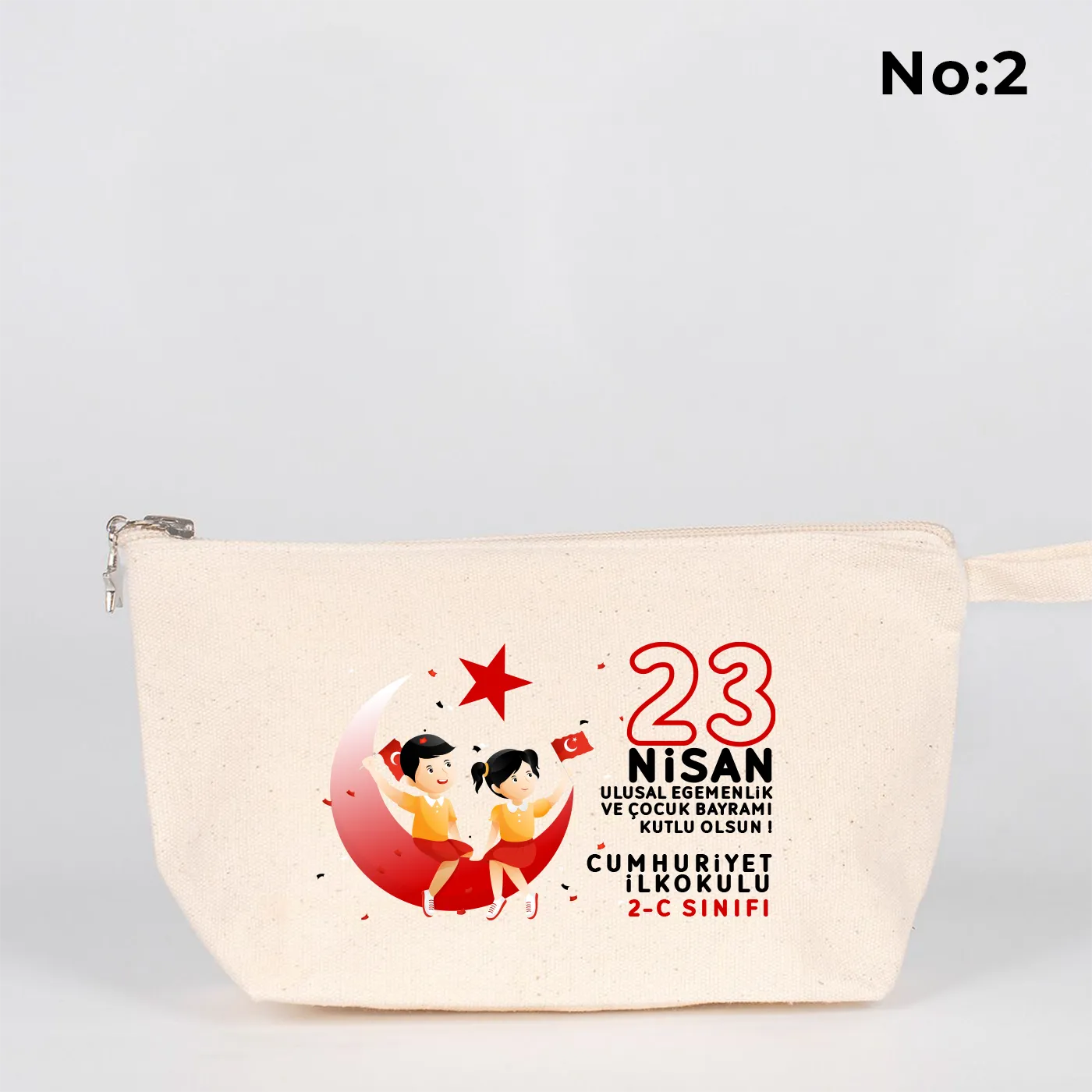 Krem renkli fermuarlı kumaş kalemlik üzerinde ay yıldız üzerinde oturan iki çocuk illüstrasyonu ve “23 Nisan Ulusal Egemenlik ve Çocuk Bayramı Kutlu Olsun” yazılı baskı