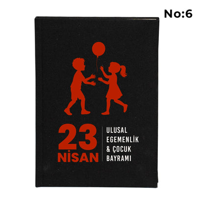 Siyah bez kaplı defter kapağı üzerinde renkli “23 Nisan Kutlu Olsun” yazı tasarımı bulunan çocuk temalı hediye defter.