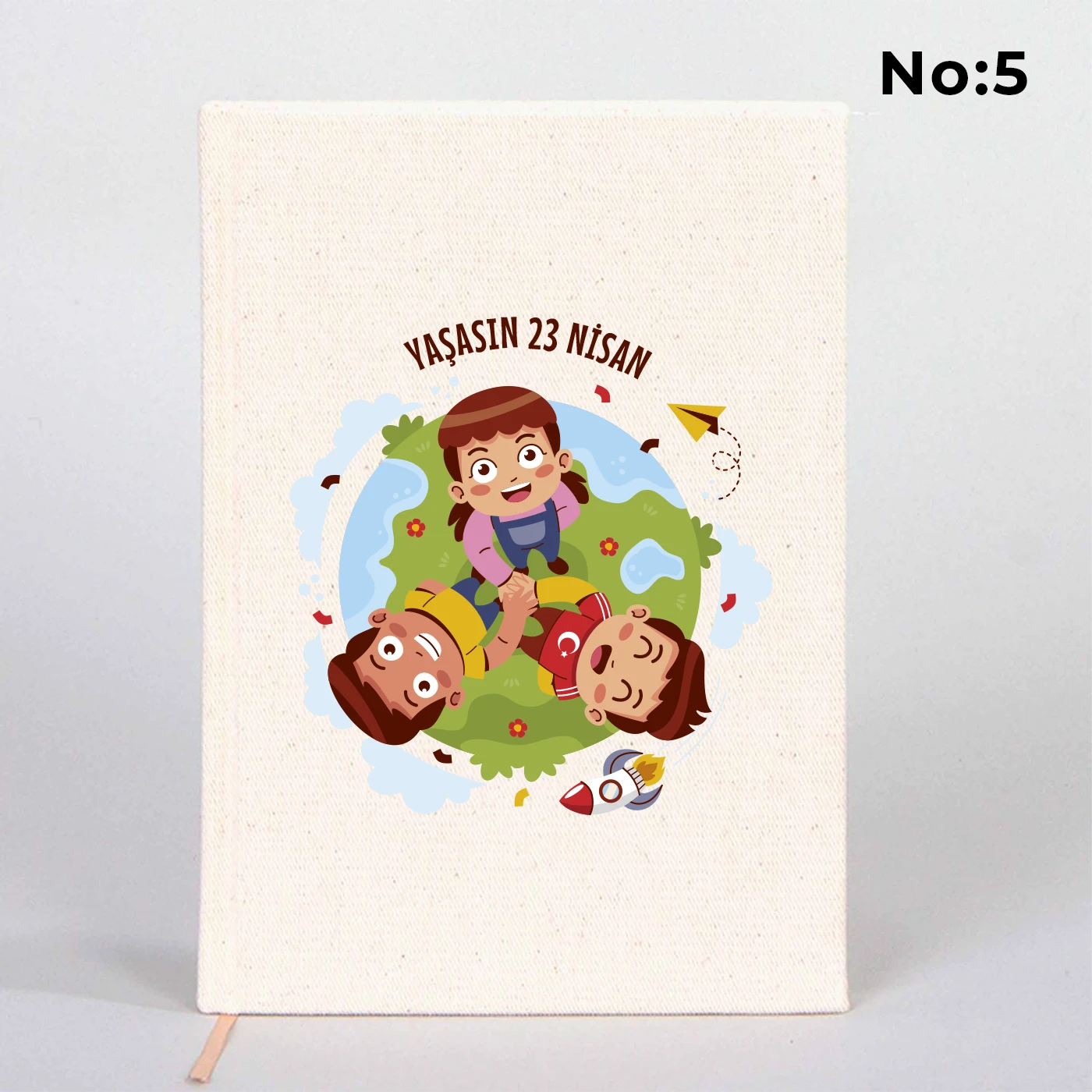 14x20 cm bez kaplı defter üzerinde renkli “23 Nisan Kutlu Olsun” yazı tasarımı bulunan çocuk temalı hediye defter.