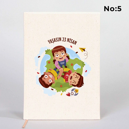 14x20 cm bez kaplı defter üzerinde renkli “23 Nisan Kutlu Olsun” yazı tasarımı bulunan çocuk temalı hediye defter.
