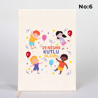 14x20 cm bez kaplı defter üzerinde renkli “23 Nisan Kutlu Olsun” yazı tasarımı bulunan çocuk temalı hediye defter.