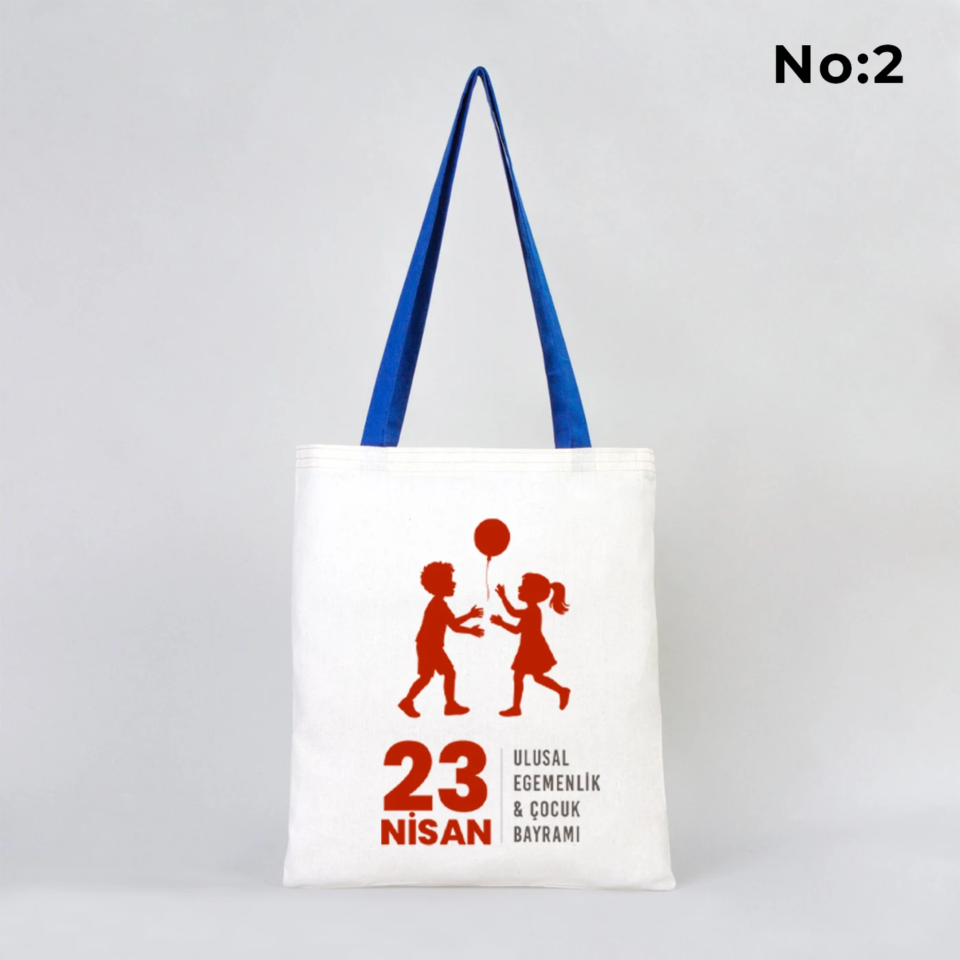 35x40 cm ham bez çanta üzerinde dünya etrafında renkli çocuk figürleri ve “23 Nisan Ulusal Egemenlik ve Çocuk Bayramı Kutlu Olsun” yazısı bulunan, mavi kulplu 23 Nisan temalı bez çanta.