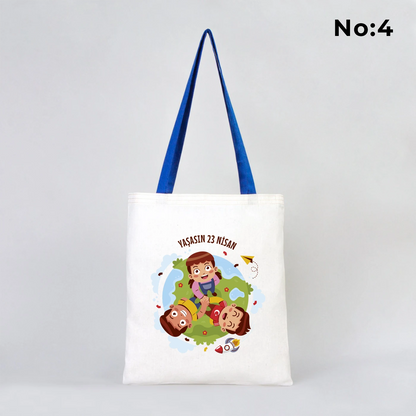 35x40 cm ham bez çanta üzerinde dünya etrafında renkli çocuk figürleri ve “23 Nisan Ulusal Egemenlik ve Çocuk Bayramı Kutlu Olsun” yazısı bulunan, mavi kulplu 23 Nisan temalı bez çanta.