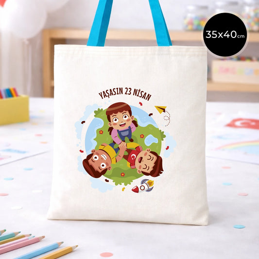 35x40 cm krem renkli bez çanta üzerinde mavi kulp detayı, “Yaşasın 23 Nisan” yazılı çocuk temalı renkli baskı ve sınıf ortamı arka planı