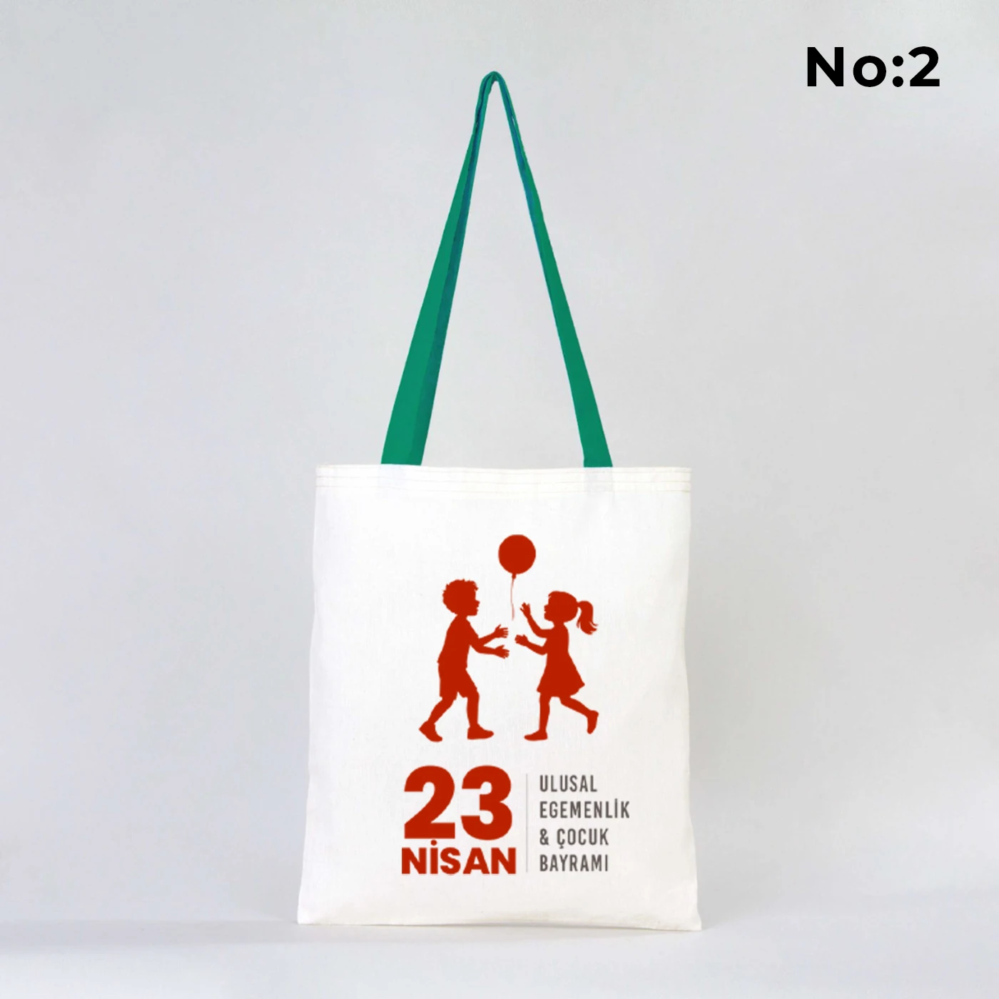 35x40 cm ham bez çanta üzerinde “23 Nisan Ulusal Egemenlik ve Çocuk Bayramı” yazısı ve Türk bayraklı kız-erkek çocuk illüstrasyonu bulunan, yeşil kulplu 23 Nisan temalı bez çanta.