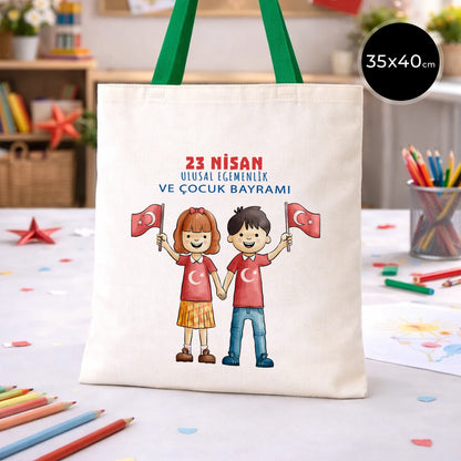 35x40 cm ham bez çanta üzerinde “23 Nisan Ulusal Egemenlik ve Çocuk Bayramı” yazısı ve Türk bayraklı kız-erkek çocuk illüstrasyonu bulunan, yeşil kulplu 23 Nisan temalı bez çanta.