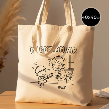 40x40 cm boyanabilir ham bez tote çanta; doğal pamuk kanvas kumaş, uzun kulplu, ön yüzünde “İyi Bayramlar” yazısı ve büyükanne–torun bayramlaşma çizimi bulunan geniş günlük bayram çantası / bayram harçlığı çantası.