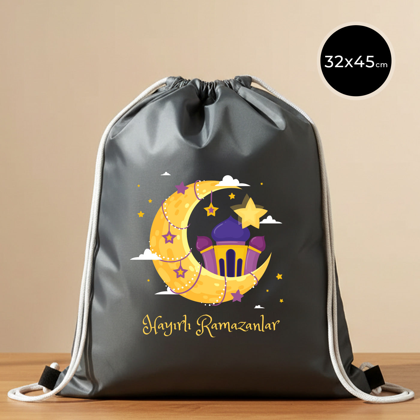 32x45 cm antrasit imperteks büzgülü sırt çantası, ip büzgülü/omuz askılı model; ön yüzünde “Hayırlı Ramazanlar” yazısı ve hilal–cami temalı renkli baskı bulunan Bayram Çantam hediyelik çanta.