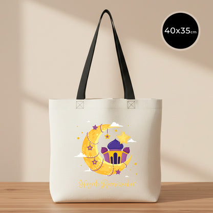 40x35 cm siyah kulplu gabardin bez çanta, krem/ham renk gövde; ön yüzünde ay-yıldız ve cami illüstrasyonlu “Hayırlı Ramazanlar” renkli baskı bulunan Bayram Çantası modeli.