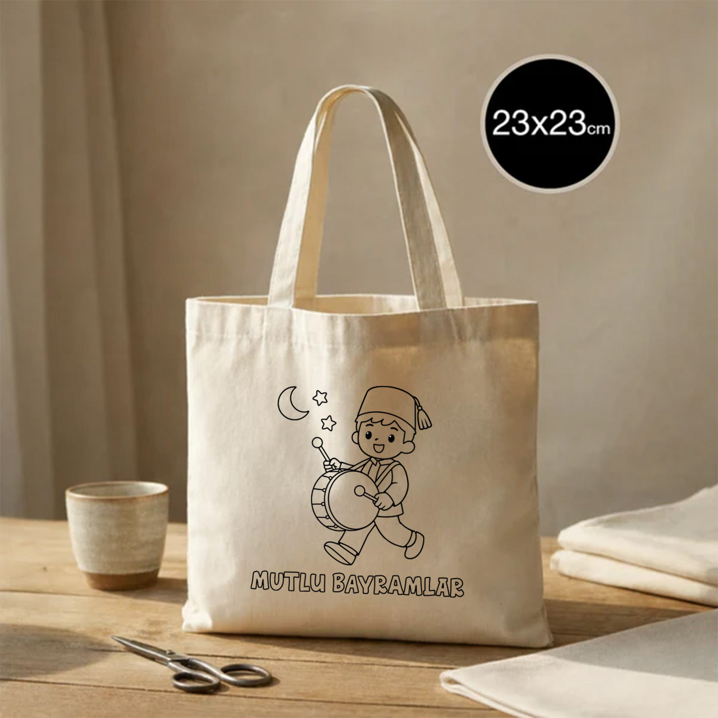 Boyanabilir 23x23 cm ham bez çanta; kısa kulplu mini tote model, üzerinde davul çalan çocuk illüstrasyonu, ay-yıldız detayı ve “Mutlu Bayramlar” yazısı bulunan Ramazan Bayramı hediyelik bez çanta.