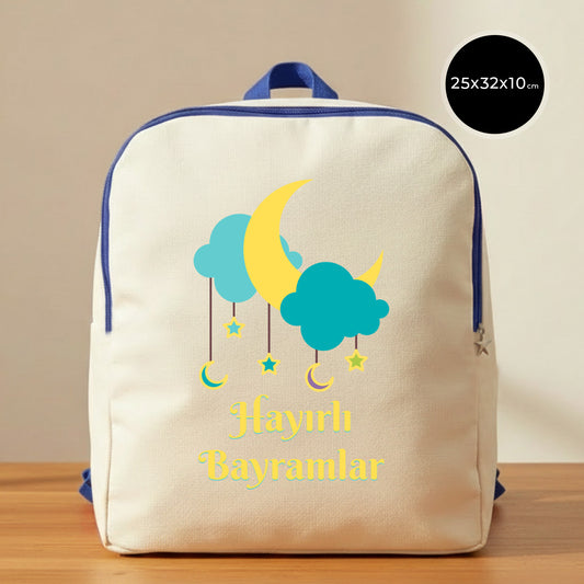 25×32×10 cm ölçülerinde doğal ham bez sırt çantası, mavi fermuar ve askılarla; ön yüzünde turkuaz bulutlar, sarı hilal ve sarkık yıldız illüstrasyonlarıyla birlikte “Hayırlı Bayramlar” yazısı, sade açık renkli arka plan ve ahşap yüzey.