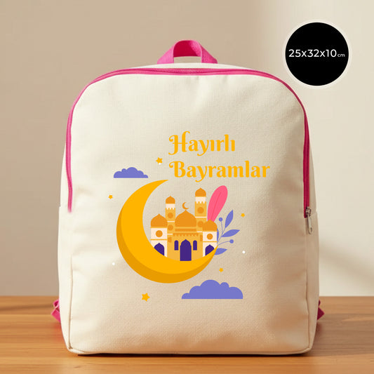 25×32×10 cm ölçülerinde doğal ham bez sırt çantası, pembe fermuar ve askılarla; ön yüzünde sarı hilal içinde cami silüeti, mor bulutlar ve yıldızlarla birlikte “Hayırlı Bayramlar” yazısı; sade açık renkli arka plan ve ahşap yüzey.